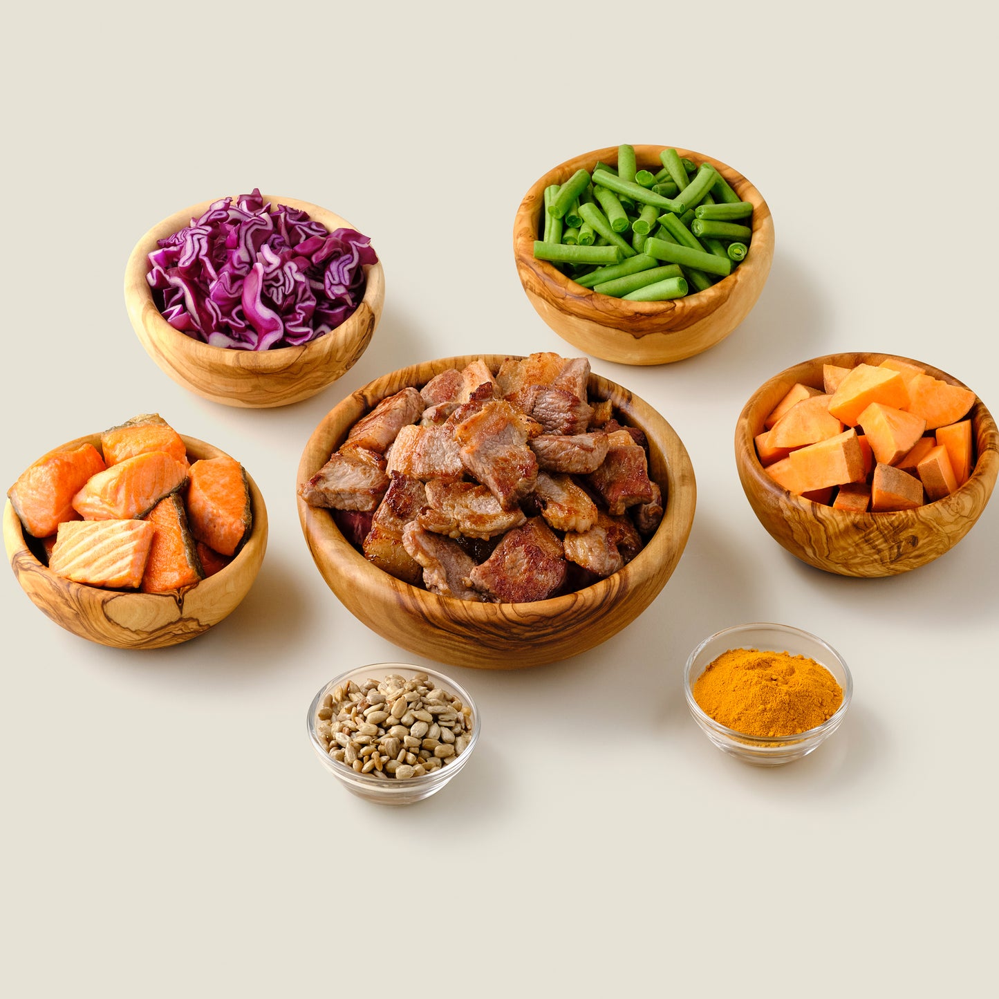 Fresh ingredients for organic grain-free lamb and salmon dog food, including premium lamb, salmon, and vegetables, displayed in wooden bowls.